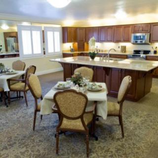 A spacious kitchen and dining area featuring elegant furniture, table settings, and modern appliances.