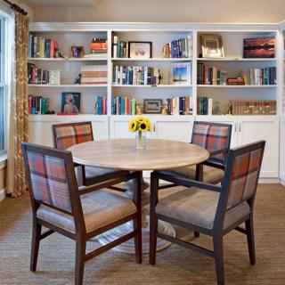 A cozy dining area with a round table and four chairs, surrounded by a well-stocked bookshelf.
