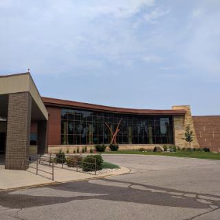 A contemporary building with a unique architectural style, featuring large glass windows and landscaped surroundings.
