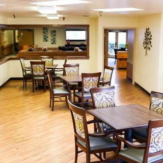 A cozy dining area with wooden tables and chairs, featuring elegant wall decor.