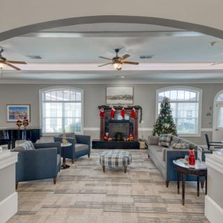 A cozy living room with Christmas decorations, featuring comfortable seating and a warm fireplace.
