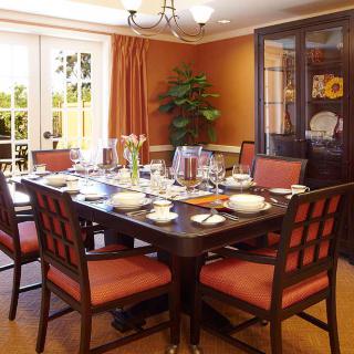 A well-decorated dining room featuring a large table set for a meal, with a chandelier overhead and a china cabinet in the background.