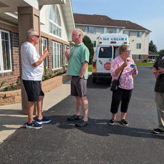 A group of four people engaged in conversation outside a building on a sunny day.