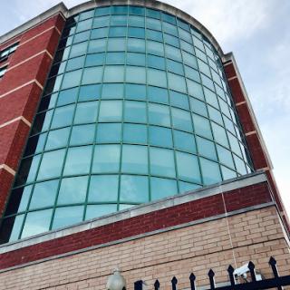 A modern building featuring a prominent glass facade and brick elements.