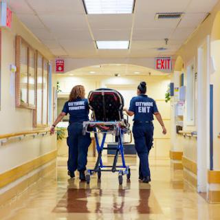 Medical personnel transporting a patient through a hospital corridor.