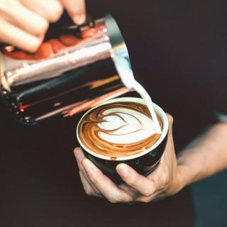 A barista skillfully creates latte art by pouring milk into a cup of coffee.