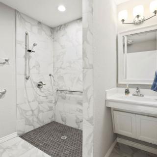A modern bathroom interior with a walk-in shower and sink area.