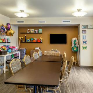 A well-lit meeting room with a long conference table, chairs, wall decorations, and colorful balloons.