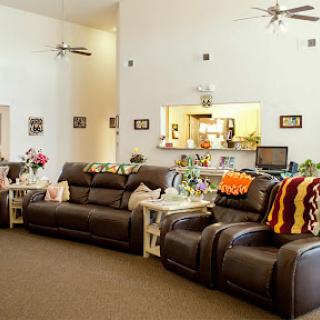 A spacious and inviting living room featuring comfortable leather sofas, decorative plants, and a cozy atmosphere.