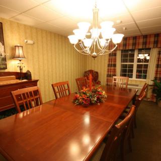 A warm and inviting dining room with a large wooden table, surrounded by chairs under a chandelier.