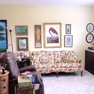 A cozy living room with vintage furniture and an eclectic mix of artwork on the walls.