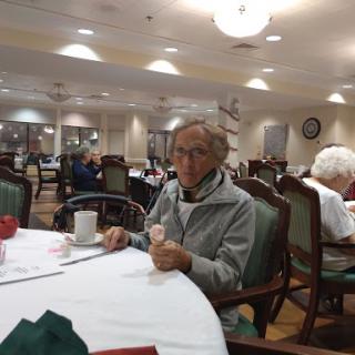 An elderly person enjoying a meal in a dining hall.