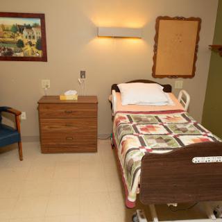 A well-furnished hospital room featuring a patient bed, nightstand, and cozy decor.