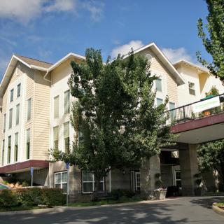 Exterior view of a hotel surrounded by trees on a sunny day.