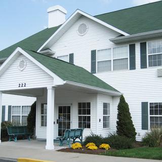 A suburban residential building with a green roof and white siding.