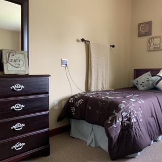 A cozy bedroom with a single bed, dresser, and decorative elements.