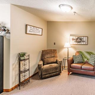 A cozy living room corner featuring a comfortable chair, a sofa with cushions, and a floor lamp for lighting.