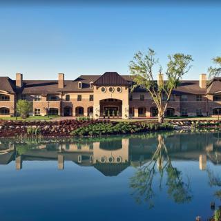 A grand building with elegant architecture is beautifully reflected in a calm lake, surrounded by lush greenery.