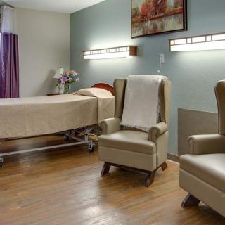 A hospital room with a patient bed and comfortable seating arrangement.