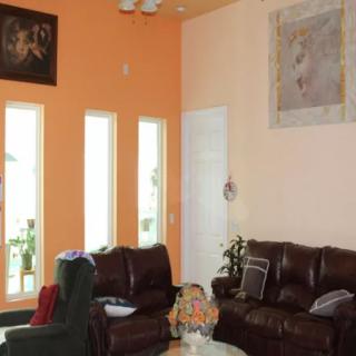 A cozy living room with orange walls and comfortable leather sofas, decorated with artwork and accent pieces.