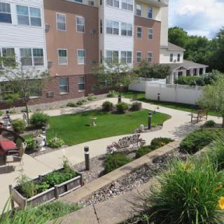 A well-maintained garden area in a residential apartment complex, featuring a manicured lawn and decorative landscaping.