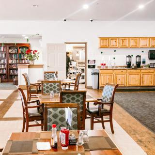 A cozy dining area with wooden tables and chairs, featuring a well-lit and inviting atmosphere.