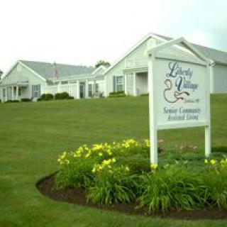 A senior community assisted living facility featuring a well-maintained lawn and garden with a prominent entrance sign.