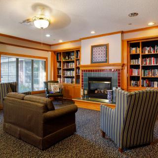 A cozy living room with a library and fireplace, featuring comfortable seating and bookshelves.