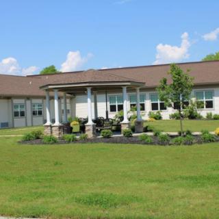 A well-maintained building surrounded by lush green grass and landscaped gardens on a clear day.
