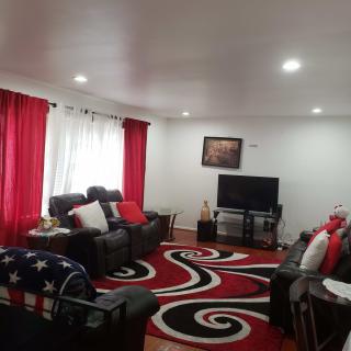 A cozy living room featuring a bold red and black rug, matching curtains, and comfortable seating centered around a television.