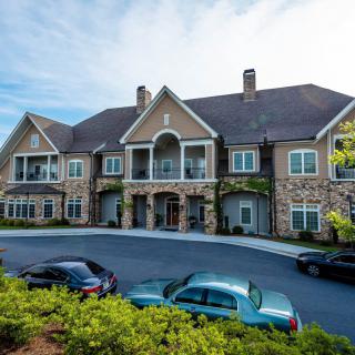 A large residential building with several cars parked in the driveway.