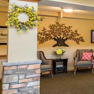 A cozy lobby area featuring decorative elements such as a wreath and metal wall art, with comfortable chairs arranged around a small table.
