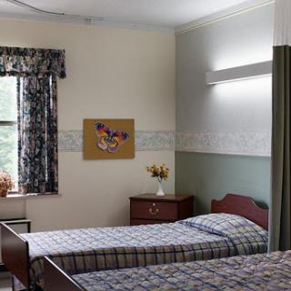 A cozy bedroom featuring two beds, a window with curtains, and decorative elements on the wall.