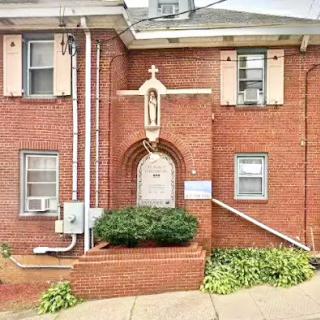 A brick church featuring a religious statue at its entrance.