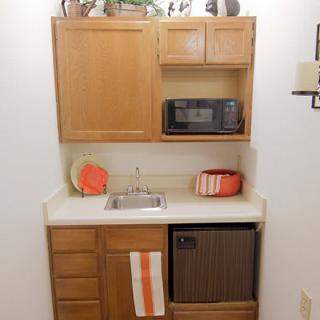 A compact kitchenette with a microwave, sink, and mini fridge.