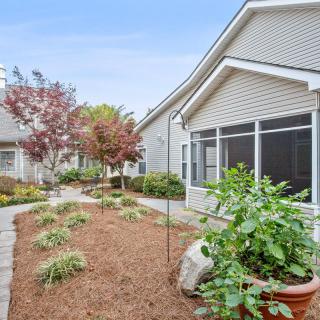 A well-maintained garden and pathway leading to a residential house with a screened porch.