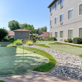 A well-maintained garden area with a putting green next to an apartment building.