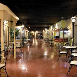 A quaint indoor hallway with tables and chairs, resembling a cafe setting.