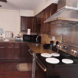 A modern kitchen with dark wooden cabinets, stainless steel appliances, and a stovetop with white dishes.