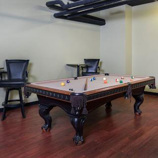 A stylish game room featuring a classic pool table with dark wooden elements.