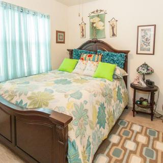 A cozy bedroom with colorful bedding and decor, featuring a wooden bed frame and matching nightstand.
