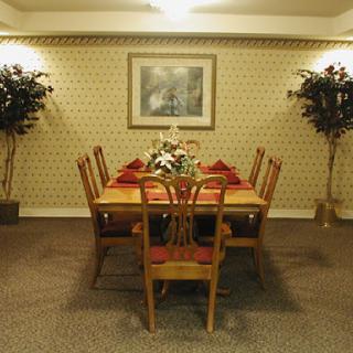 A cozy dining room setup featuring a wooden table surrounded by chairs, adorned with decorative plants and wall art.