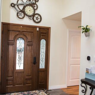 A stylish home entryway featuring a wooden door and decorative clock wall art.