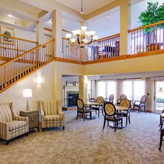 A spacious and elegantly designed living room with a staircase, dining tables, and comfortable seating.