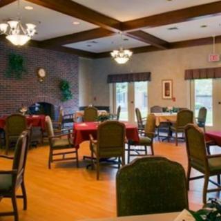 A cozy dining room with several tables and chairs, featuring a brick wall and soft lighting.