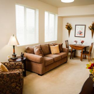 A cozy living room with a sofa, dining set, and neutral decor.