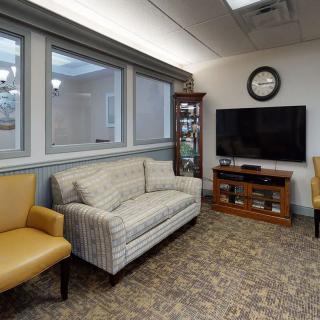 A comfortable waiting room with a sofa, chairs, and a television.