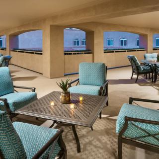 A cozy outdoor seating area with cushioned chairs and small tables, perfect for an evening gathering.