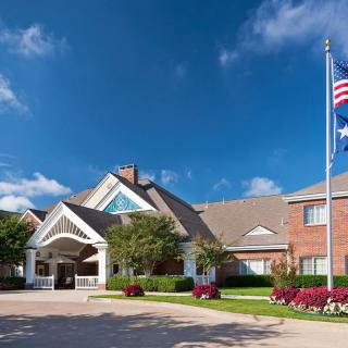 A well-maintained building with a triangular entrance, surrounded by greenery, under a clear blue sky.