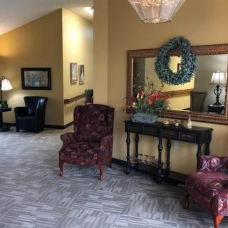 A cozy lobby area with decorative furniture and a mirror on the wall.